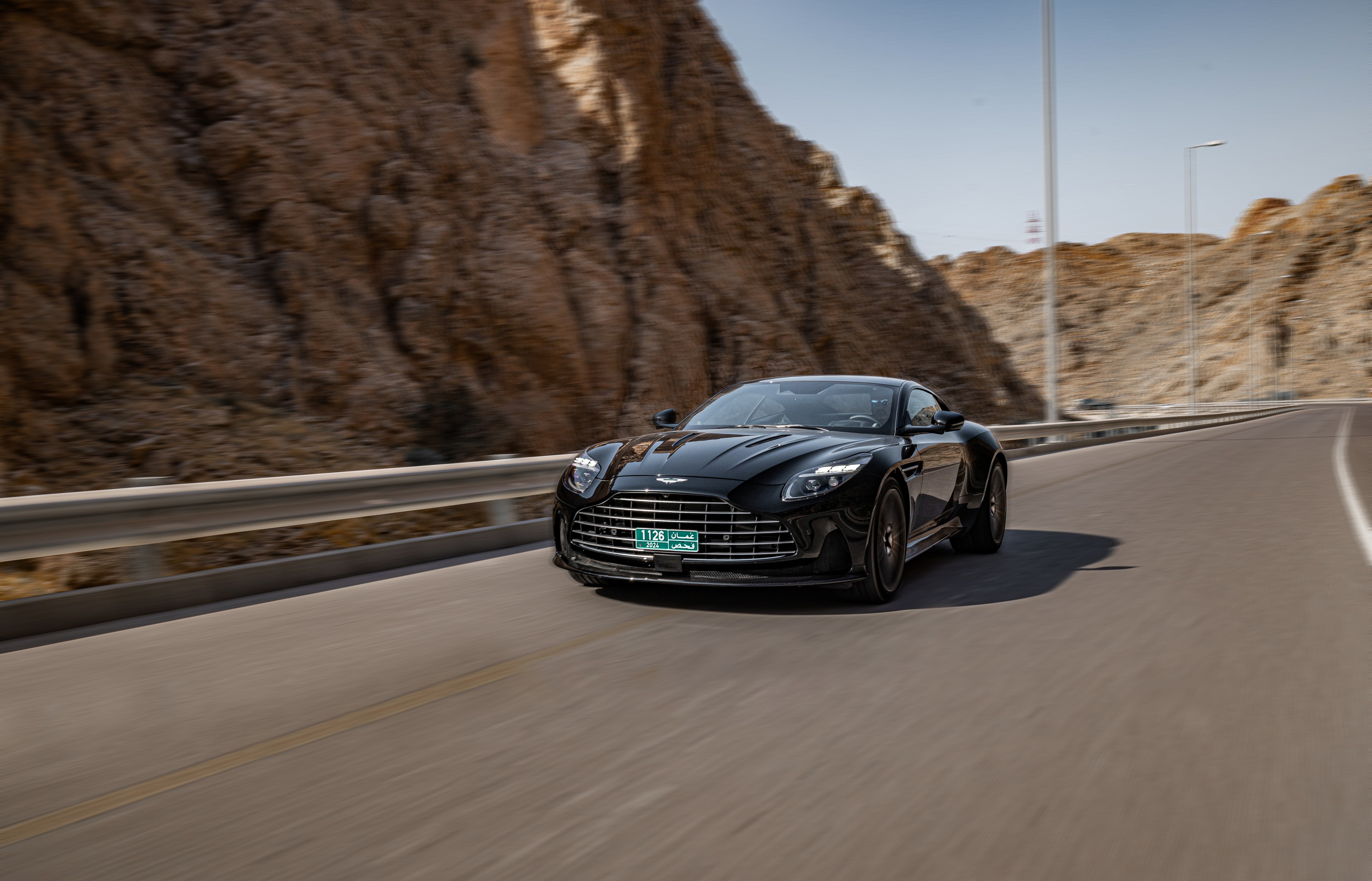 Black Aston Martin rolling through a mountain road